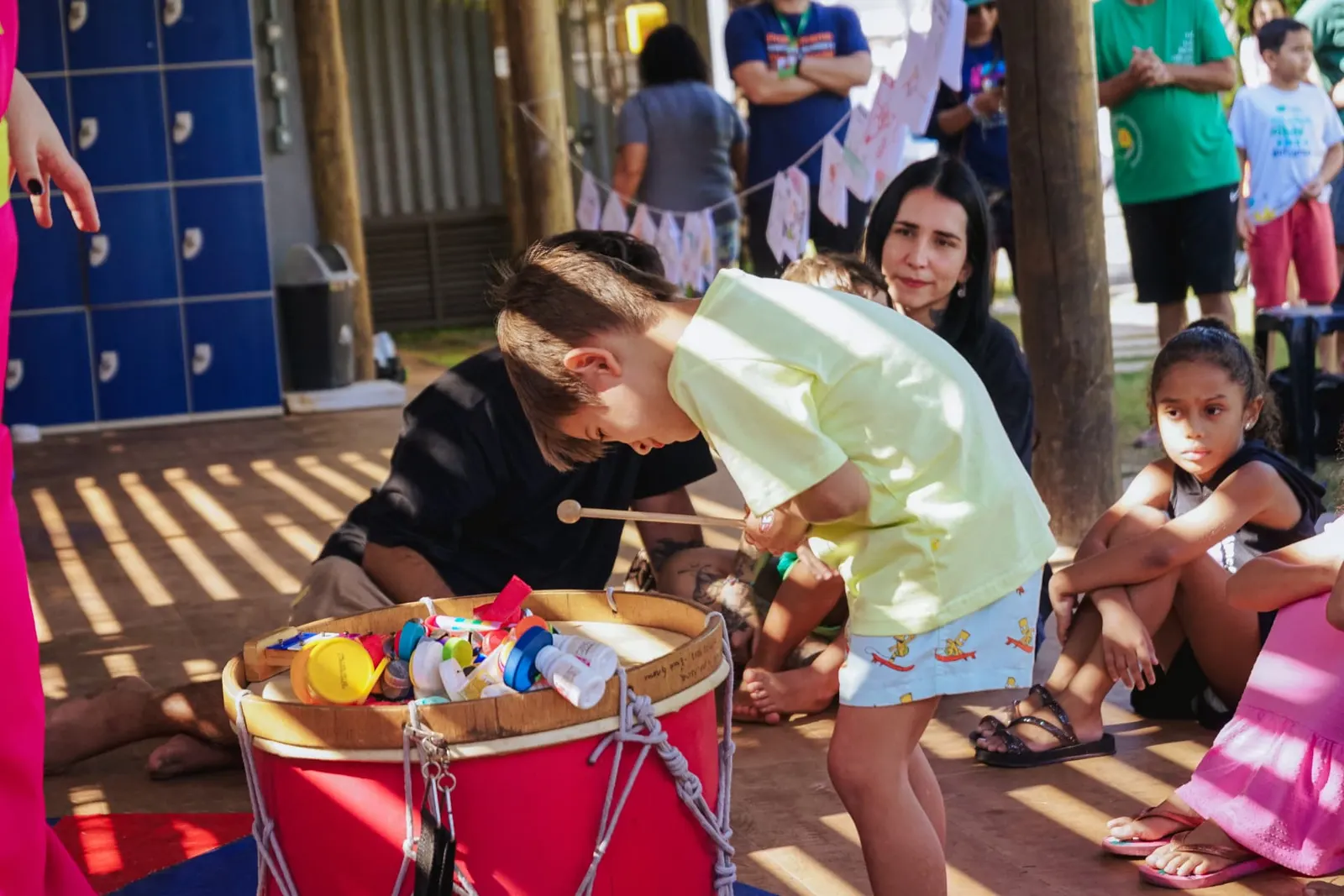 Criança tocando tambor em oficina sensorial ao ar livre
