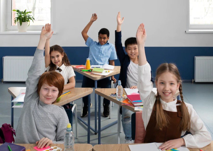 Foto de 5 crianças em sala de aula, simulando os 4 pilares da educação