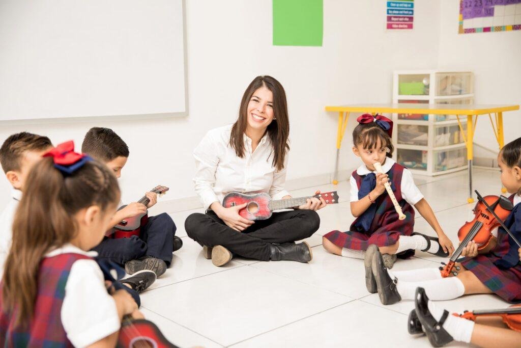 Foto de uma professora e sua turma fazendo trabalho de musicalização