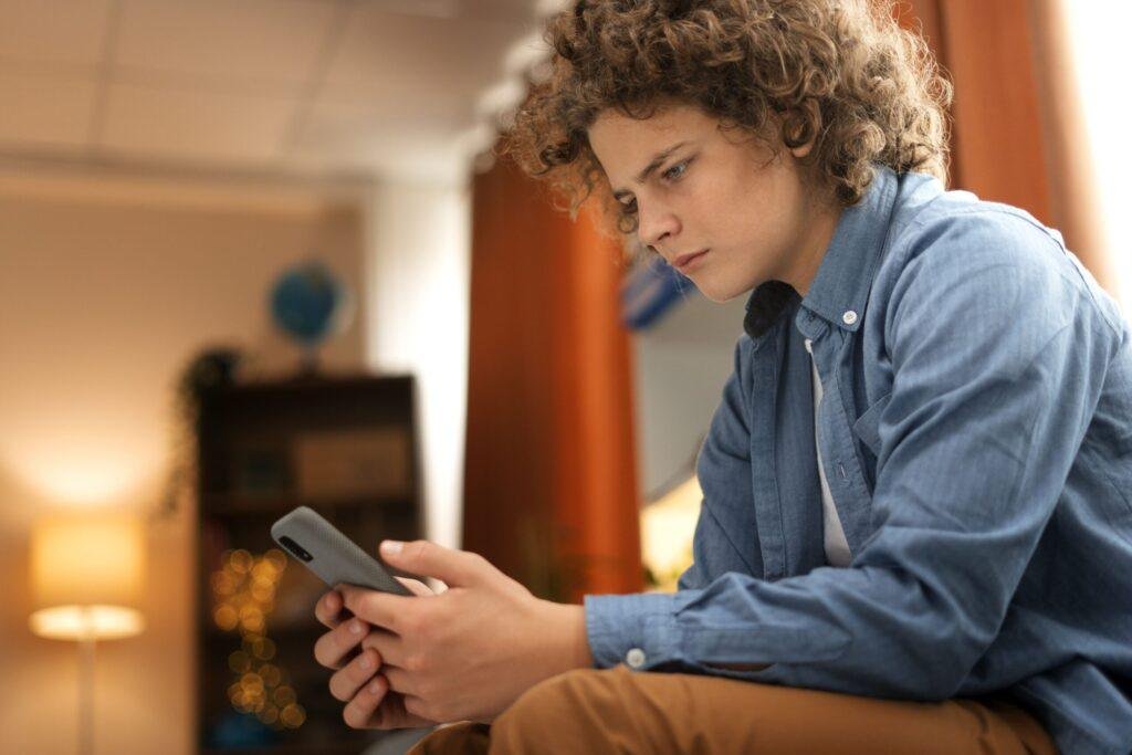 Foto de um adolescente no celular, simulando um caso de nomofobia