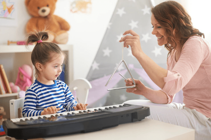 Foto de uma professora e uma criança tocando teclado