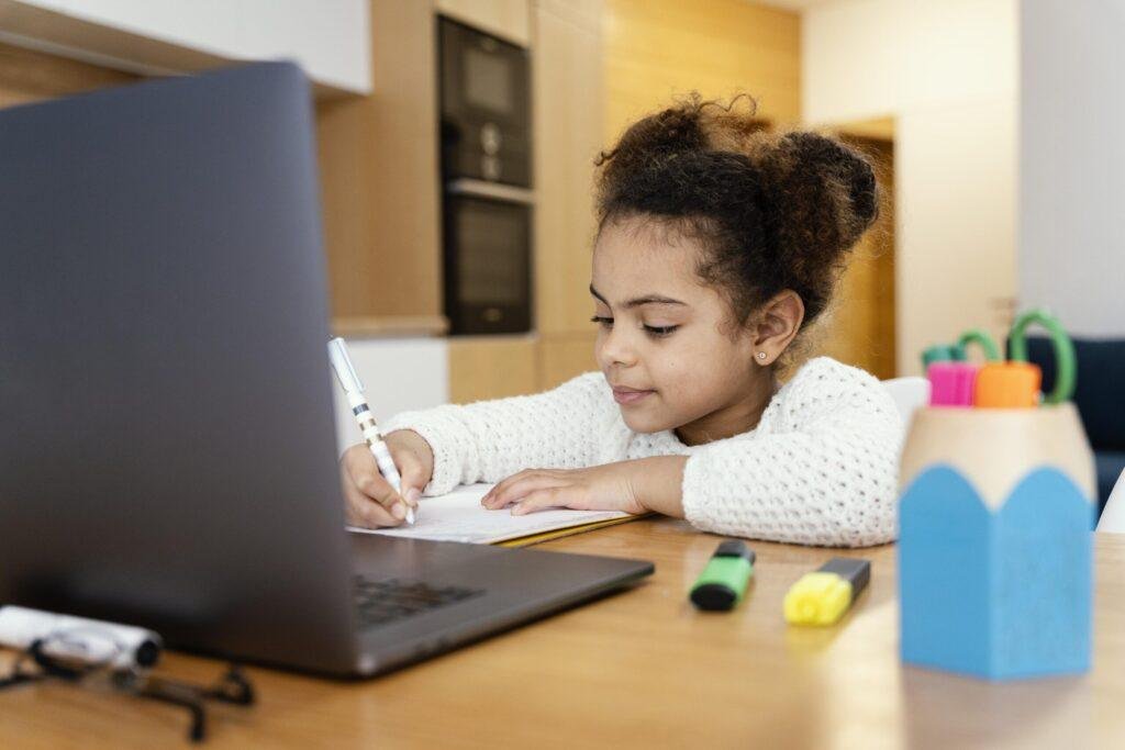 Foto de uma criança fazendo aula remota no notebook